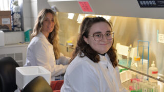 两名研究人员在研究人员凯特·麦克纳马拉（Kate MacNamara）实验室的设备前微笑