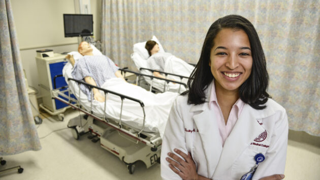 一名医疗专业人员，站在专门的临床培训室，配备了医院的床和设备。